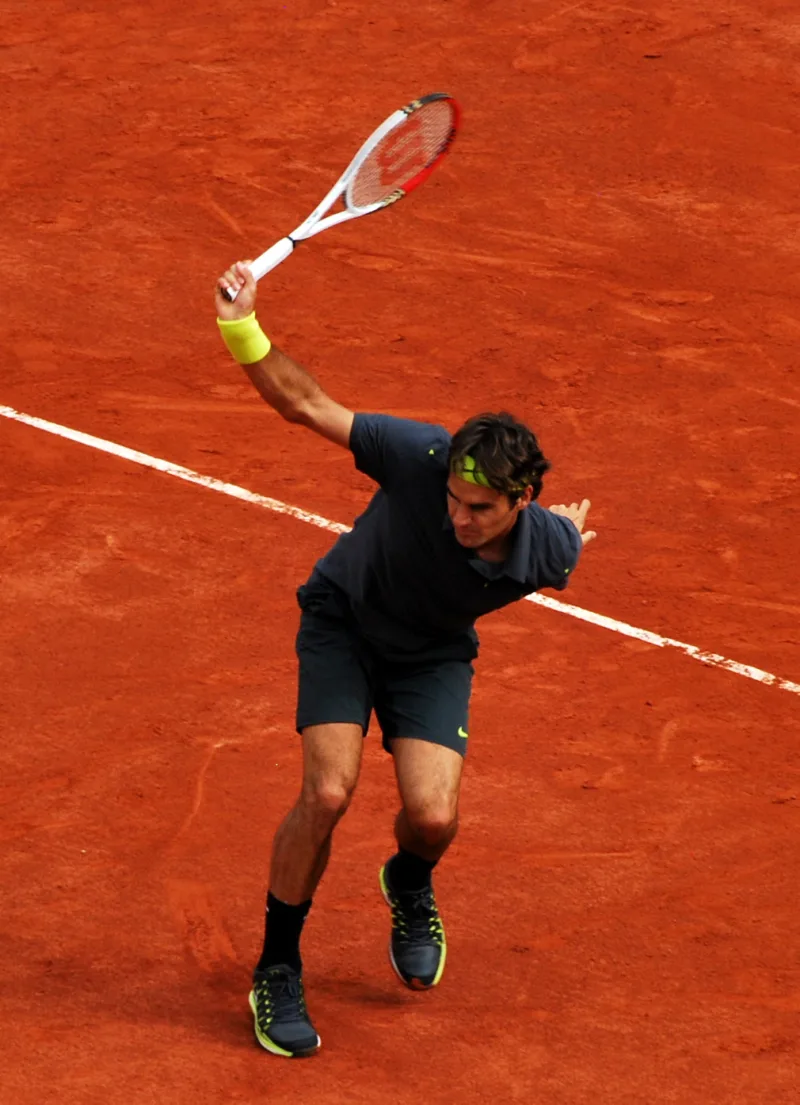 Federer completes a one-handed backhand with the Wilson logo visible on his racquet