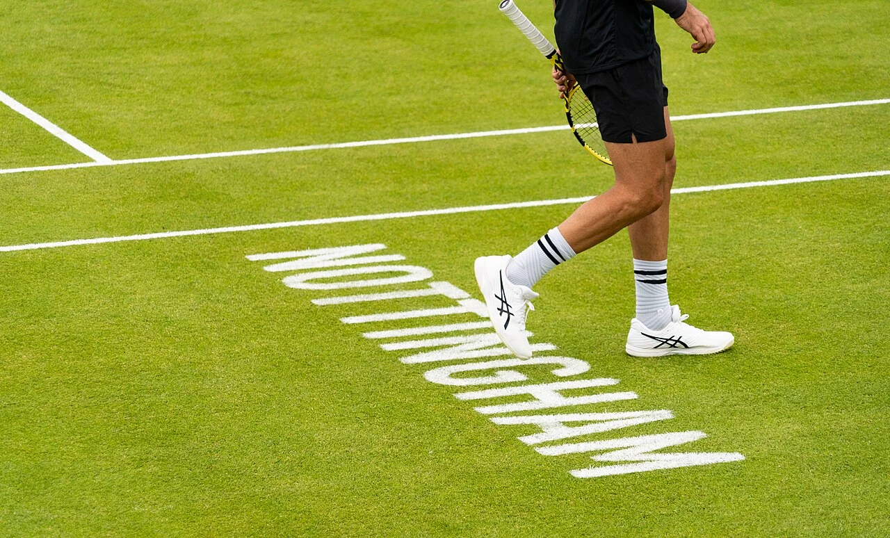 La scritta Nottingham su un campo in erba con una parte del corpo di un tennista visibile