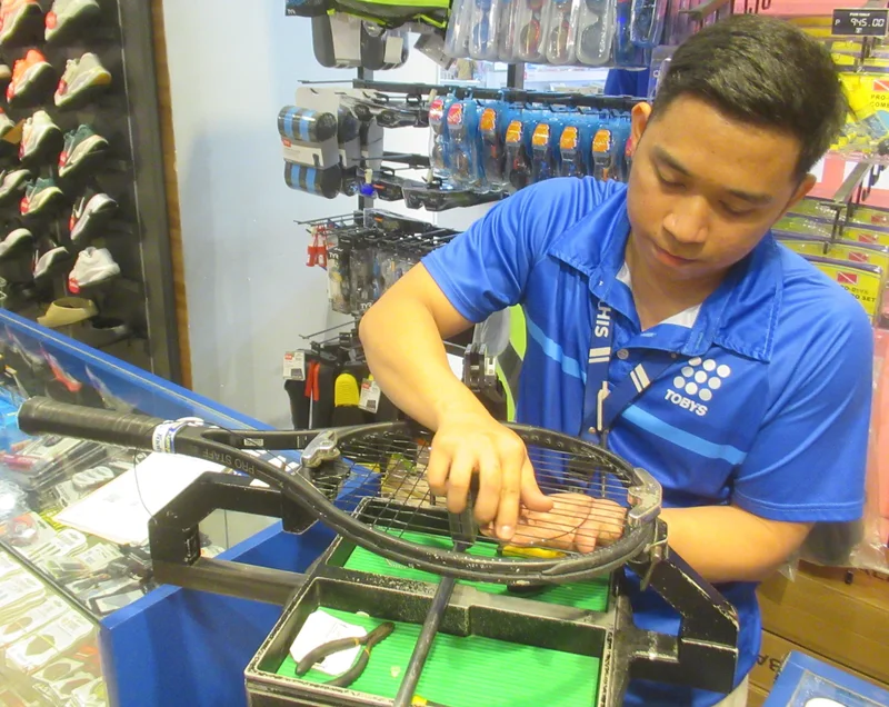 A technician at a tennis stringing machine
