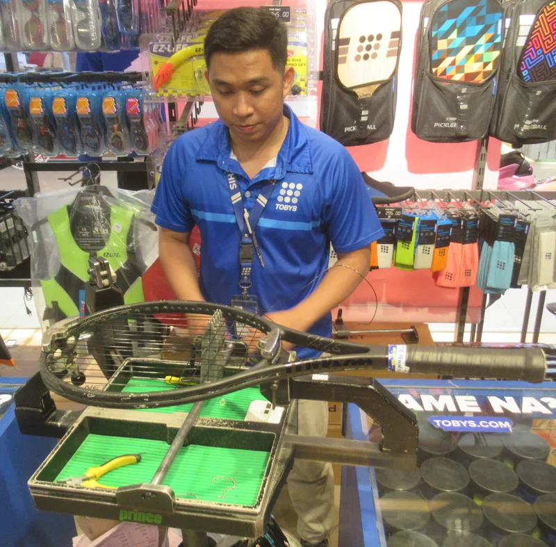 A technician at a tennis stringing machine