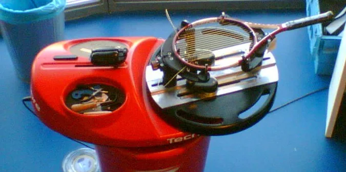 A tennis racquet mounted on a stringing machine