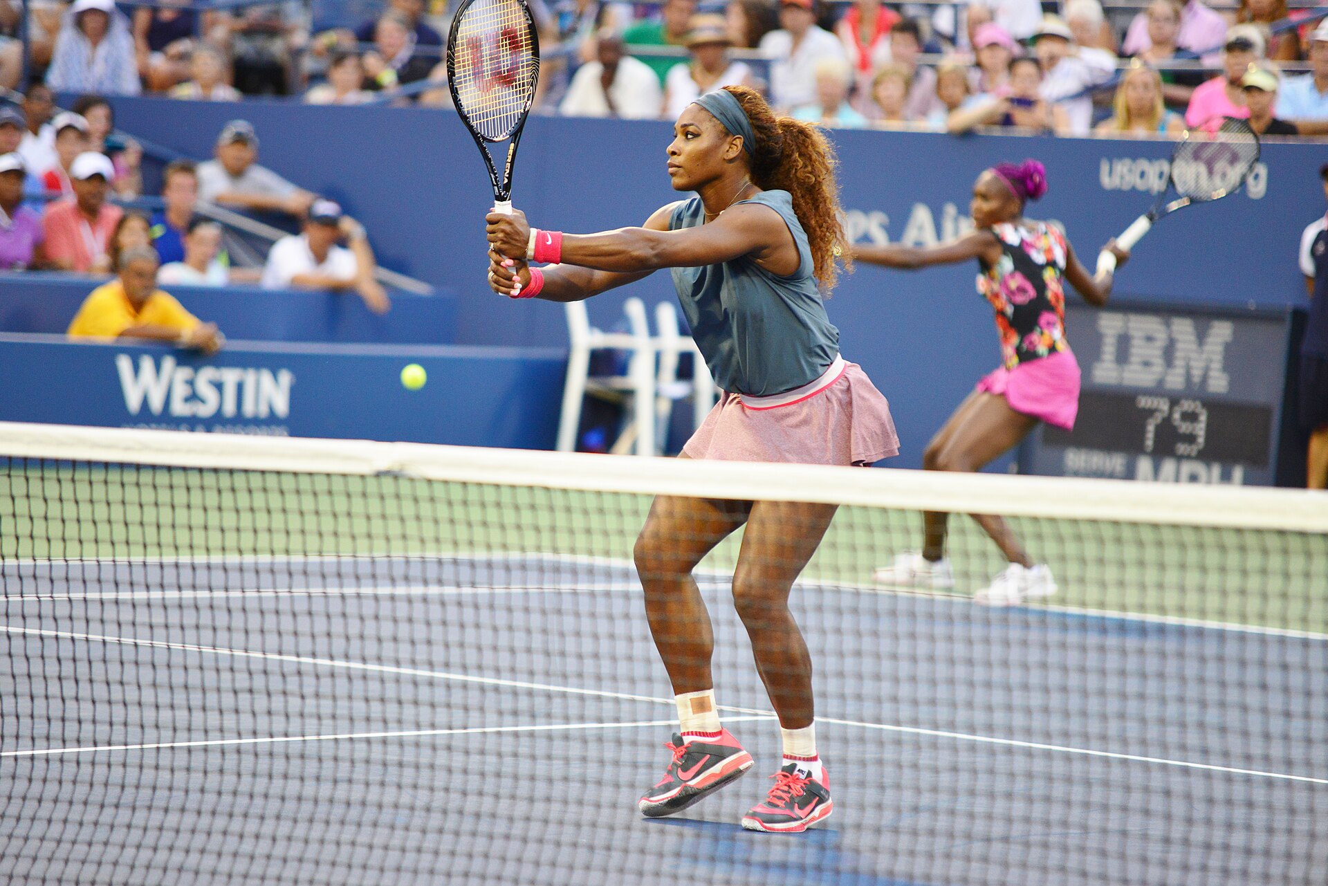 Serena Williams in Netznähe, dahinter Venus Williams bei den US Open 2013